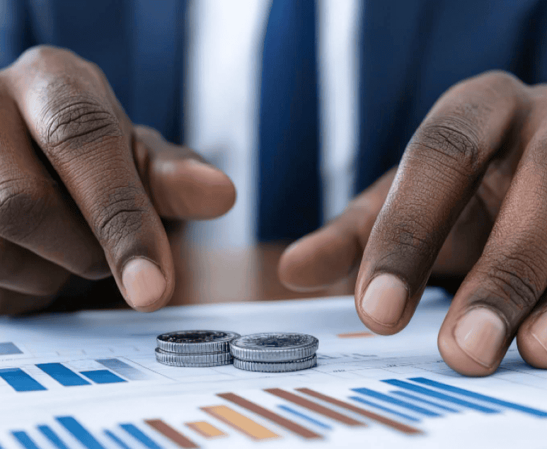 Close-up of a businessman analyzing financial charts with stacked coins, symbolizing monetary policy impact on liquidity and growth.